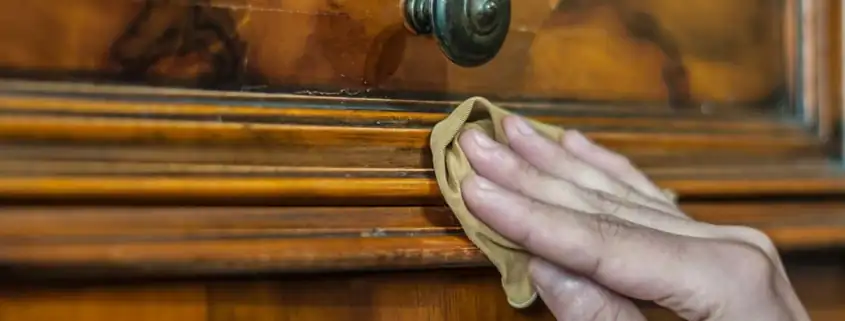 Natural Farben Onlineshop - Kategorie Holzpflegemittel Hand poliert eine hölzerne Kommode mit einem weichen Tuch und Holzpflegemittel